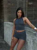 Conjunto deportivo gris compuesto por un top halter con logo dorado y un short con cintura fruncida.