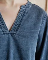 Blusa celeste de manga larga con escote en V y detalle bordado en el cuello.