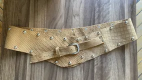 Cinto de cuero con hebilla metálica y diseño texturizado símil piel de cocodrilo, serpiente o charol.