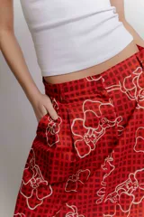 Falda midi de popelina de algodón negra con estampado geométrico de cuadros en tonos blancos, amarillos y rosados, con bolsillos laterales.