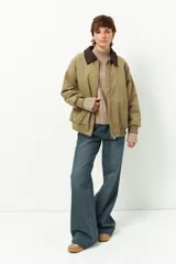 Campera negra tipo barn jacket, de corte oversized, con bolsillos laterales, puños y cuello de pana marrón. Interior capitoneado.