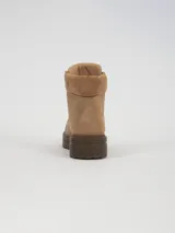 Borcego de caña corta color beige, con cordones al tono, cuello acolchado y suela de goma dentada en color marrón oscuro.