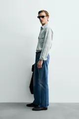 Camisa de algodón con efecto lavado, diseño a cuadros en tonos celestes y beige, cuello solapa, manga larga con puños abotonados y bolsillos frontales con solapa.