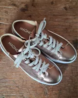 Zapatilla urbana de cuero con diseño combinado en color dorado metalizado y gamuza en tono tostado. Presenta cordones al tono, suela de goma blanca y detalles en cuero marrón en la parte posterior.