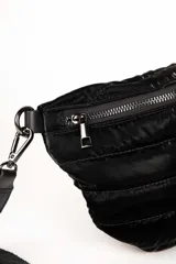 Riñonera plateada con diseño capitoneado, correa de tela negra regulable y cierre superior.