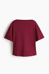 Remera de manga corta con escote bote y hombros caídos, confeccionada en punto suave de algodón de color bordó, con diseño holgado y cintura de corte recto.