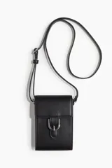 Bolso bandolera chico color negro, de cuero sintético, con correa ajustable y solapa con hebilla metálica decorativa y botón a presión oculto.