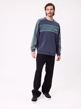 Sweater de cuello redondo marca Rusty, con diseño de bloques de color en azul marino y verde, con detalles de líneas blancas. Presenta el logo de la marca bordado en el pecho.