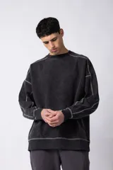 Buzo de cuello redondo con calce oversize, confeccionado en frisa de algodón con efecto de lavado gastado. Presenta costuras a contratono visibles y diseño de recortes en los hombros y mangas.
