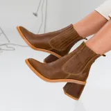 Botas tipo chelsea de cuero vacuno negro, con elásticos laterales, taco cuadrado y punta fina.