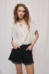 Short de jean blanco de tiro medio con silueta relajada y detalle de ruedo desflecado con flecos.