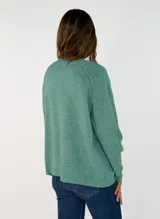 Sweater de punto con escote en V, manga larga y corte holgado. Presenta un diseño liso con costura central vertical en el frente y terminaciones acanaladas en puños y ruedo.