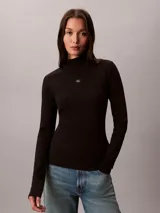 Top negro de manga larga con cuello tortuga, confeccionado en punto fino elástico de algodón BCI y lycra. Presenta un diseño ajustado de corte slim fit con un pequeño parche con el monograma de la marca en el centro del pecho.