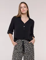 Blusa verde de calce holgado y caída fluida, confeccionada en tejido tipo crepé. Cuenta con cuello camisero con solapa, escote en V y cierre parcial al frente con tres botones metálicos. Las mangas son largas con puños abotonados.