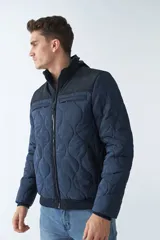 Campera de nylon azul marino para hombre con capucha, cierre frontal con cremallera, bolsillos laterales y frontales. El modelo usa talle M.