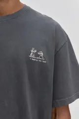 Remera de algodón color verde oscuro, de corte holgado y manga corta, con pequeño estampado gráfico en el pecho.