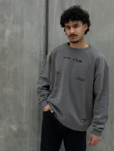 Buzo gris con cuello redondo, mangas largas y puños y bajo acanalados. Estampado frontal con el logo "Osten" y la frase "A mindset of becoming".