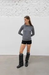 Botas de caña alta confeccionadas en cuero negro, con diseño holgado y tres correas horizontales con hebillas metálicas doradas en la parte superior. Presentan punta redondeada y taco bajo cuadrado.