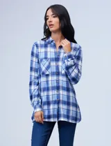 Camisa de manga larga con estampado de cuadros azules y blancos, cuello con solapa, abertura central con botones y bolsillos delanteros.