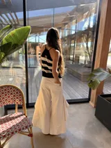 Musculosa de punto tejida en hilo de algodón, con diseño a rayas horizontales en color negro y crudo, escote halter con tirantes ajustables para atar al cuello.