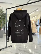 Canguro oversize marrón con capucha, bolsillo tipo canguro y diseño estampado en la espalda con el texto "Be Brave" y detalles tipográficos en color blanco.