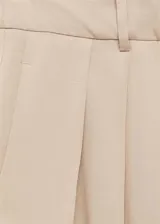 Pantalon de corte wideleg color beige, con tiro medio, detalle de pinzas frontales, trabillas para cinturon y cierre frontal con boton, gancho y cremallera.