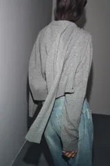 Chaqueta de tejido de punto color verde musgo, de corte cropped, con cuello redondo y cierre frontal de botones oscuros.