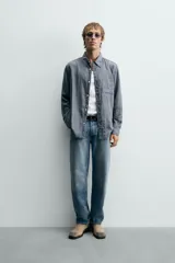Camisa de corte relajado confeccionada en tejido fluido con mezcla de viscosa, presenta un diseño de rayas verticales, cuello solapa, cierre frontal con botones, manga larga con puño abotonado y un bolsillo de plastrón en el pecho.