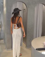 Vestido largo de tejido de punto calado color crema, con escote halter y espalda descubierta.