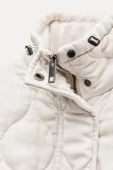 Chaleco gris acolchado con cuello alto, cierre frontal con cremallera metálica, bolsillos de plastrón en delantero y bajo ajustable con cordones.