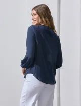 Blusa azul marino de Zac & Rachel con cuello a la base, abertura central con botones y detalle de broderie en el frente. Tiene mangas largas con terminación elastizada.