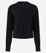 Suéter negro de punto leve, corte boxy, cuello redondo y mangas largas con puños y bajo acanalados.