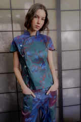 Top de tafeta elastizada con estampado floral, cuello mao con ribete en contraste, mangas cortas y cierre frontal cruzado con botones a la vista.