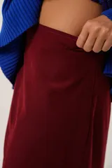 Falda larga color borgoña, confeccionada en tela suave con acabado tipo piel de durazno y cierre invisible lateral.