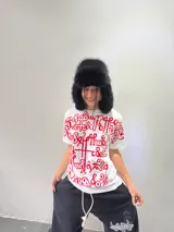 Remera blanca de corte regular con estampado frontal de gran tamaño en color rojo, con diseño de caligrafía abstracta. Confeccionada en algodón de alto gramaje, cuenta con cuello reforzado y grifa de la marca en la manga.