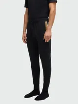 Pantalones deportivos negros de corte ajustado con una franja dorada en el lateral.