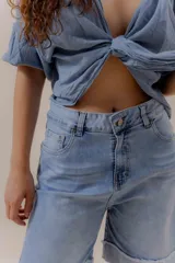 Bermuda de denim celeste, de tiro medio, corte relajado y largo por encima de la rodilla. Presenta doble ruedo con detalle desflecado.
