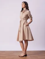 Vestido camisero blanco de algodón con cuello con solapa, delantera abotonada, mangas 3/4 regulables con presilla y botón, y cintura con lazo de ajuste.