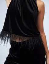 Conjunto de dos piezas compuesto por una musculosa de cuello alto con detalle de plumas en el ruedo y un pantalón de corte recto, ambos confeccionados en terciopelo negro.
