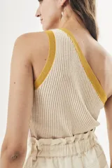 Top tejido color crema con rayas verticales y ribete amarillo en el escote asimétrico.