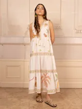 Vestido largo color crudo con estampado de motivos tropicales y cuello con detalle estampado en azul.