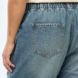 Jeans mom de color azul claro, con cintura elástica fruncida, bolsillos delanteros tipo cargo y puños elásticos en los tobillos.