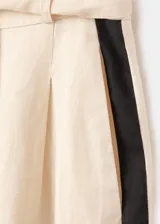 Pantalón wide leg de lino color beige con franjas negras en contraste a los costados, tiro alto, bolsillos laterales y cinturón incorporado.