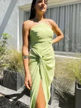 Vestido largo color naranja, con escote halter cruzado y falda tipo pareo con tajo lateral. Confeccionado en tela crepé con caída fluida.