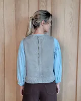 Chaleco de denim con diseño a rayas verticales, cuello redondo y corte recto. Presenta pespuntes en contraste y detalle de aberturas en los laterales.