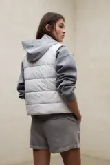 Chaleco acolchado blanco sin mangas, con diseño de franjas horizontales, cuello alto y cierre frontal con botones a presión. Modelo Olimpo de Ecoalf.