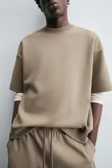 Sudadera de manga corta color marrón oscuro, con cuello redondo y bajo acabado en rib. Presenta un corte relajado y holgado (boxy fit).