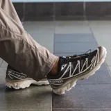 Championes Salomon modelo XT-6, diseñados para uso urbano y deportivo. Presentan una combinación de tonos marrones y detalles en crema, con estructura de malla y refuerzos de TPU. Incluyen sistema de cordones rápidos y suela técnica de alto rendimiento.