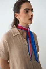 Pañuelo liviano y translúcido de diseño romboidal, con estampado inspirado en un atardecer uruguayo en tonos rosa, rojo y azul, ideal para usar atado al cuello.
