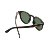 Lentes de sol Indie modelo Ozzy, con montura redonda de madera color ébano y lentes polarizadas verdes.